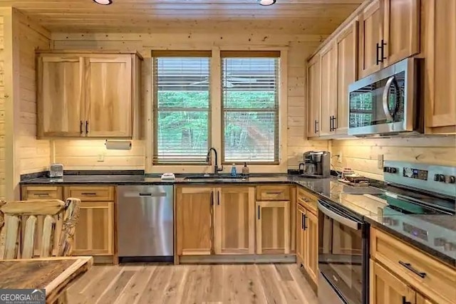 kitchen featuring wood walls, light hardwood / wood-style floors, sink, appliances with stainless steel finishes, and wooden ceiling