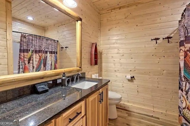 bathroom featuring toilet, vanity, wood walls, and wooden ceiling