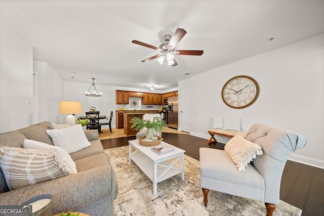 living room featuring ceiling fan with notable chandelier and light hardwood / wood-style flooring