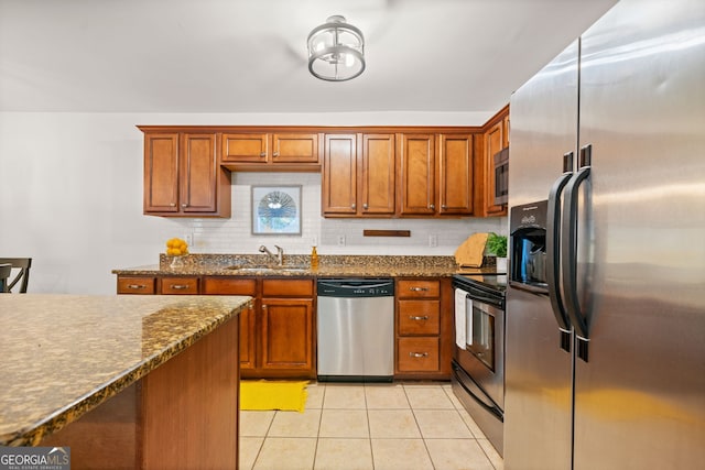 kitchen with decorative backsplash, stainless steel appliances, sink, light tile patterned floors, and dark stone countertops