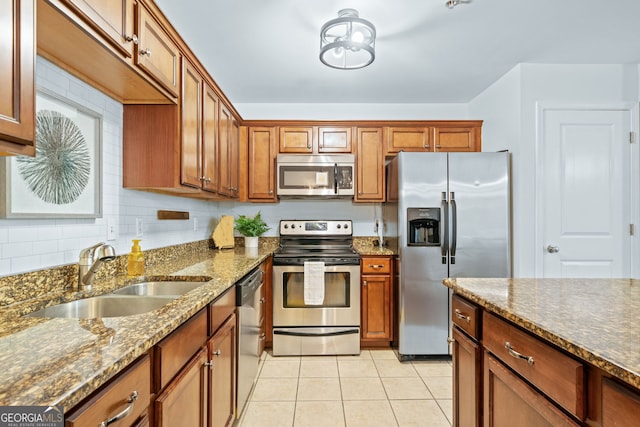 kitchen with sink, light stone counters, decorative backsplash, light tile patterned floors, and appliances with stainless steel finishes