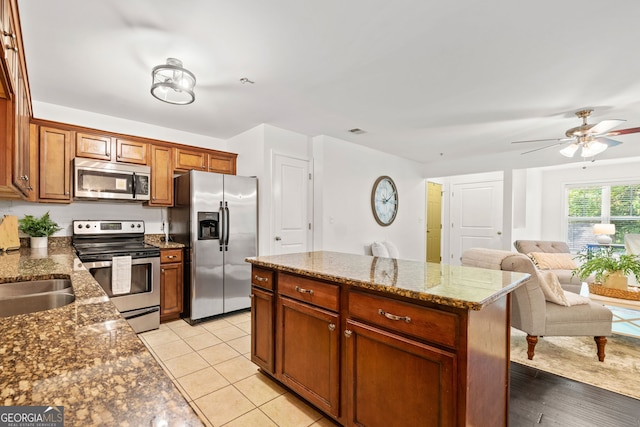 kitchen featuring appliances with stainless steel finishes, a center island, stone countertops, and light tile patterned floors