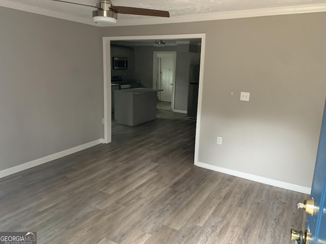 empty room featuring ceiling fan, ornamental molding, and dark wood-type flooring