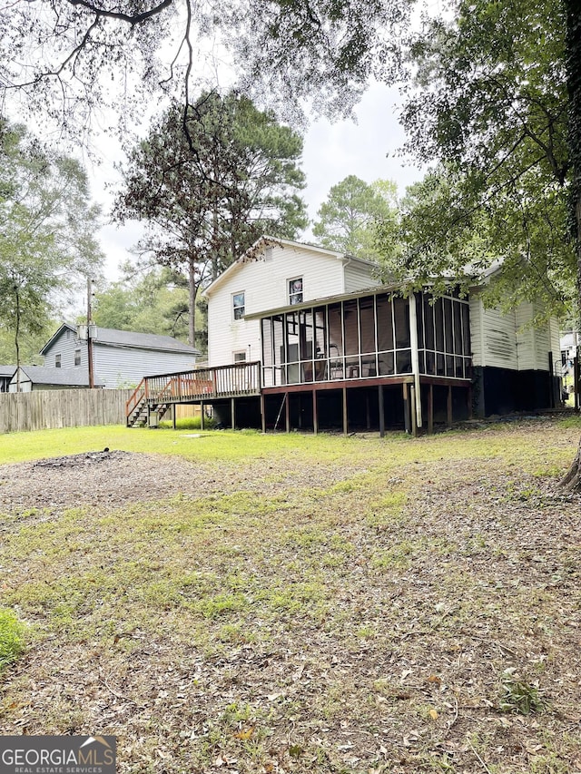 rear view of property featuring a sunroom and a deck