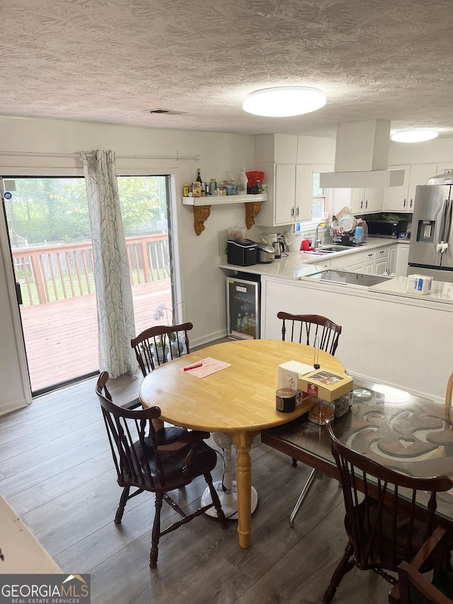 dining room featuring hardwood / wood-style flooring, sink, a textured ceiling, and wine cooler