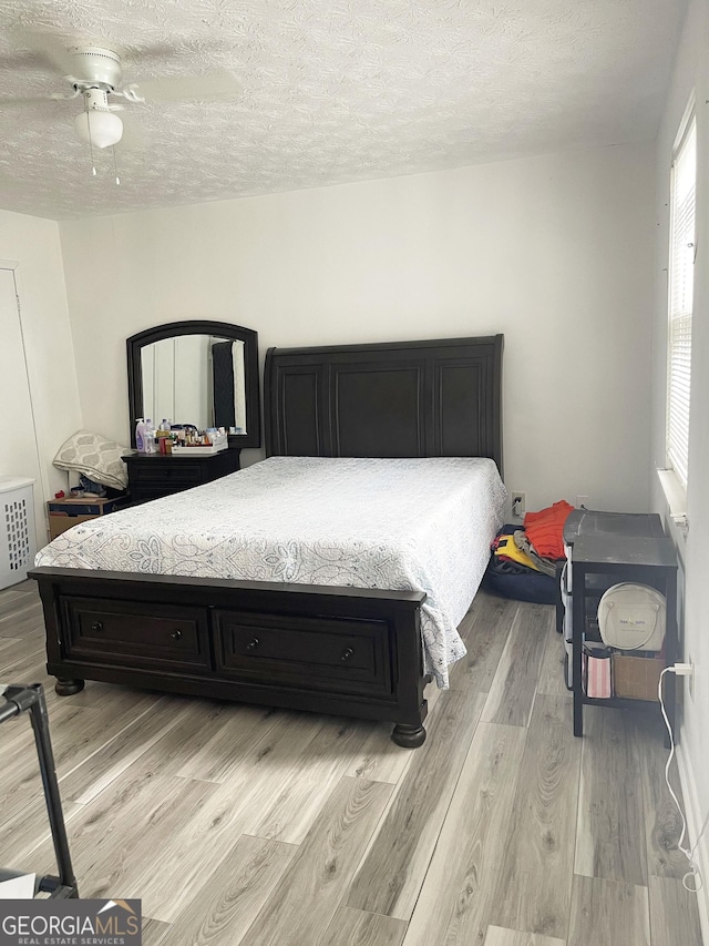 bedroom featuring ceiling fan, a textured ceiling, and light wood-type flooring