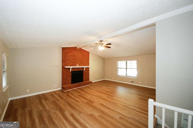 unfurnished living room featuring ceiling fan, a fireplace, lofted ceiling with beams, and wood-type flooring