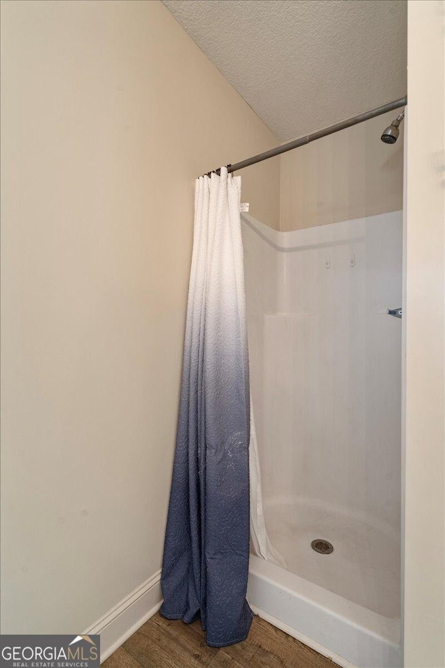 bathroom with hardwood / wood-style floors, curtained shower, and a textured ceiling