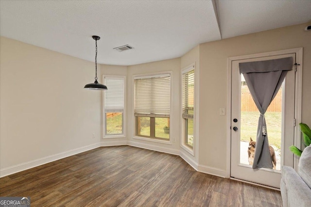 unfurnished dining area featuring a textured ceiling and dark wood-type flooring