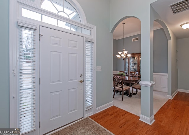 entryway featuring hardwood / wood-style floors, ornamental molding, and an inviting chandelier