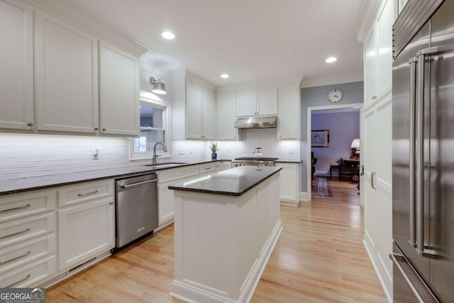 kitchen with sink, a center island, stainless steel appliances, dark stone counters, and white cabinets