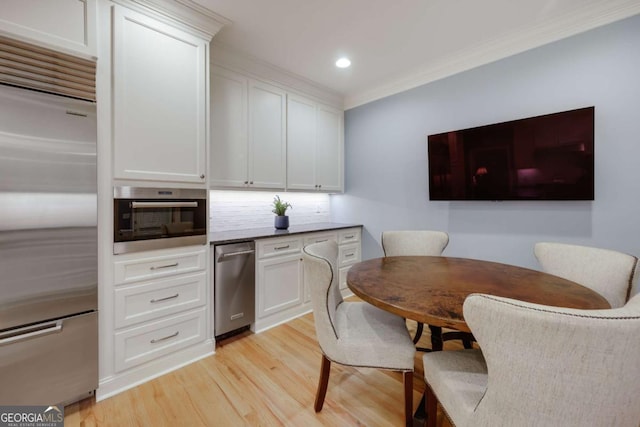 kitchen featuring stainless steel built in refrigerator, decorative backsplash, ornamental molding, light hardwood / wood-style floors, and white cabinetry