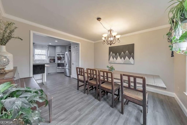 dining space with dark wood-type flooring, crown molding, and a chandelier