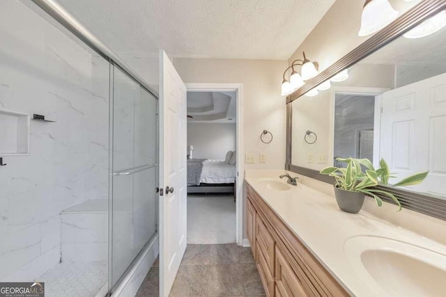 bathroom with a shower with shower door, a textured ceiling, and vanity