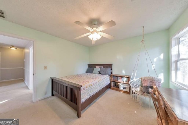 bedroom featuring ceiling fan, light colored carpet, and a textured ceiling