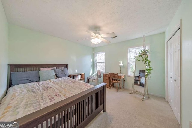 carpeted bedroom with a textured ceiling, ceiling fan, and a closet