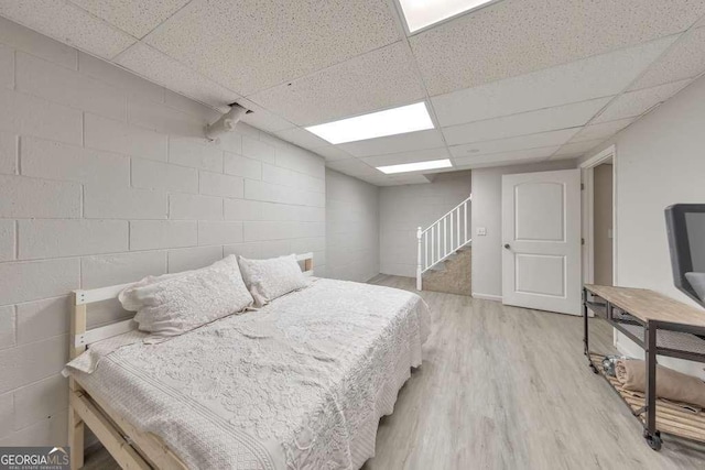 bedroom with a paneled ceiling and light wood-type flooring