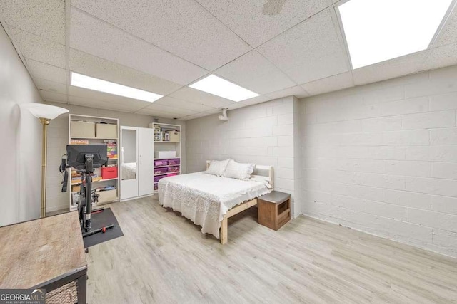 bedroom featuring a drop ceiling and light wood-type flooring