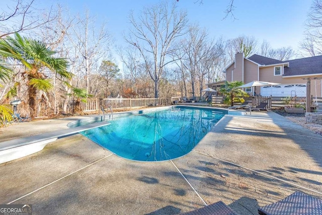 view of swimming pool featuring a patio area and a diving board