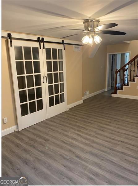 spare room featuring ceiling fan, a barn door, and dark wood-type flooring