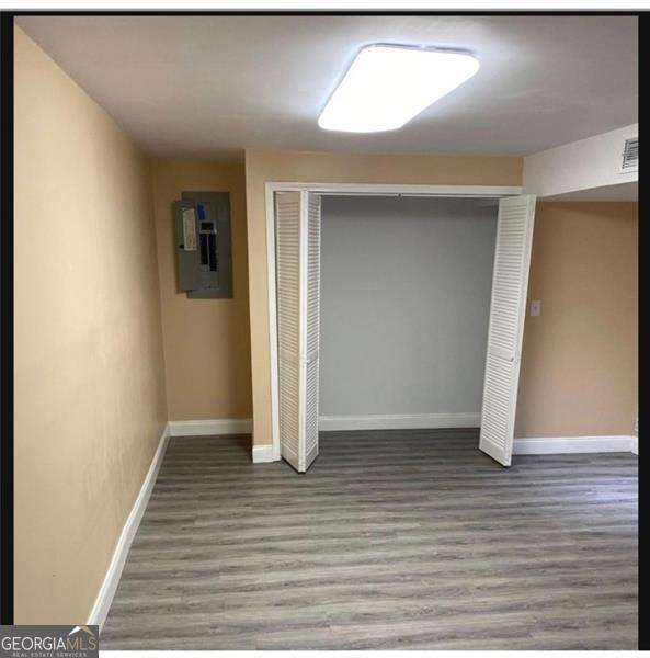 unfurnished bedroom featuring wood-type flooring, electric panel, and a closet