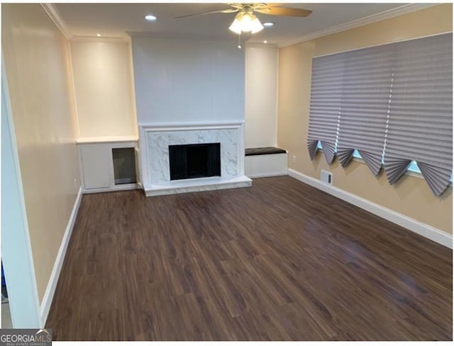 unfurnished living room with dark wood-type flooring, ceiling fan, ornamental molding, and a premium fireplace