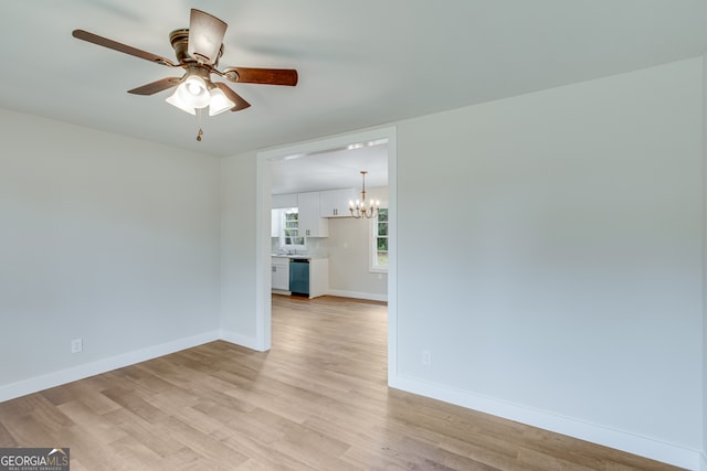 spare room featuring light hardwood / wood-style flooring and ceiling fan with notable chandelier