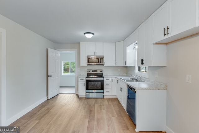 kitchen with white cabinetry, sink, appliances with stainless steel finishes, and light hardwood / wood-style flooring