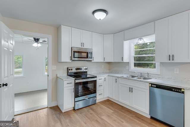 kitchen with sink, white cabinets, stainless steel appliances, and light hardwood / wood-style floors