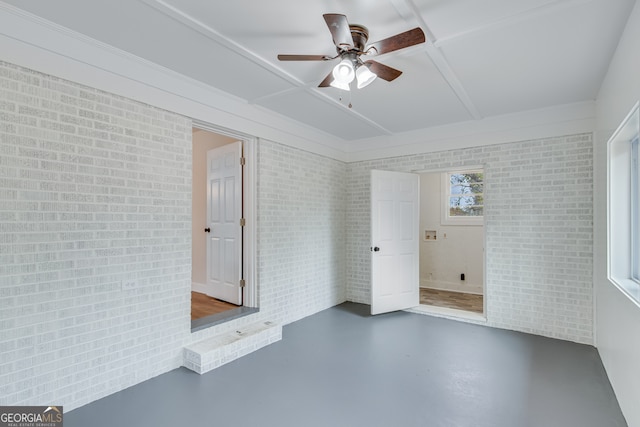 empty room featuring ceiling fan, concrete floors, and brick wall