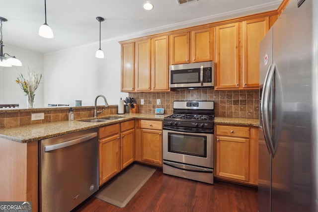 kitchen with light stone countertops, appliances with stainless steel finishes, kitchen peninsula, sink, and hanging light fixtures