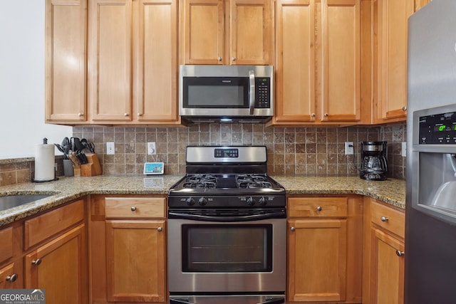 kitchen with backsplash, light stone countertops, and stainless steel appliances