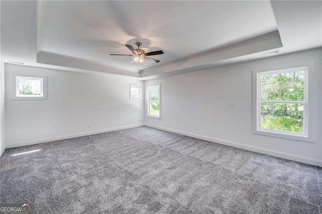 carpeted spare room with a tray ceiling and ceiling fan