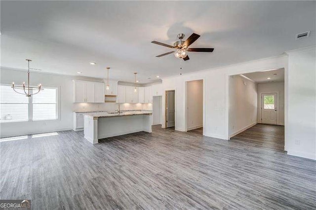 kitchen with white cabinets, ceiling fan with notable chandelier, a center island with sink, and hanging light fixtures