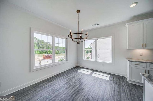 unfurnished dining area with a healthy amount of sunlight, dark hardwood / wood-style flooring, ornamental molding, and a chandelier