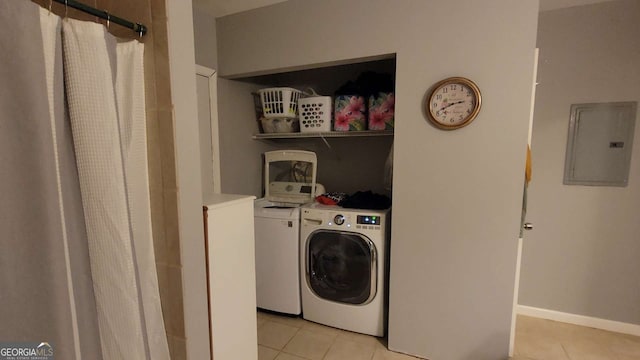 washroom featuring electric panel, washer and clothes dryer, and light tile patterned floors