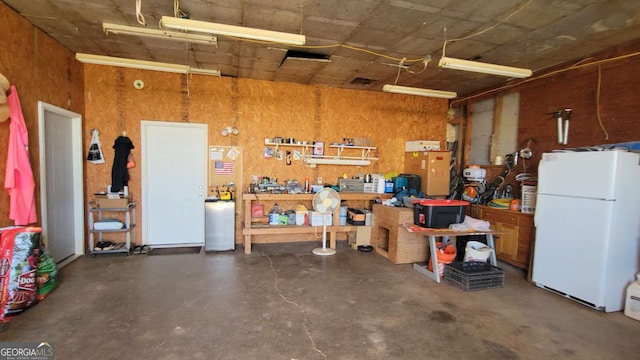 garage featuring a workshop area and white refrigerator