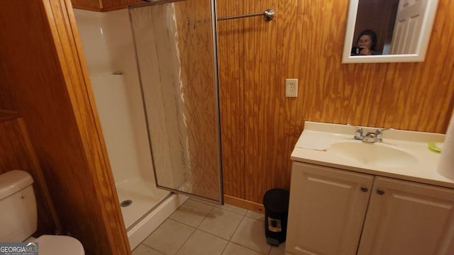 bathroom with walk in shower, tile patterned floors, toilet, wooden walls, and vanity