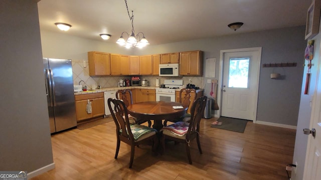 kitchen with an inviting chandelier, light hardwood / wood-style flooring, backsplash, pendant lighting, and white appliances