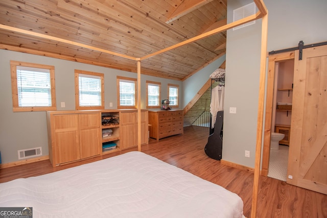 bedroom with ensuite bath, wooden ceiling, a barn door, vaulted ceiling with beams, and light hardwood / wood-style flooring