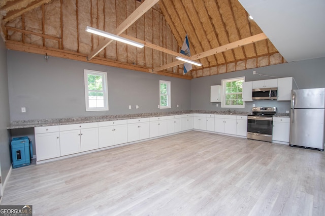 kitchen with a wealth of natural light, white cabinets, and appliances with stainless steel finishes