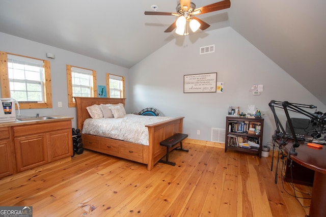 bedroom featuring light hardwood / wood-style floors, vaulted ceiling, ceiling fan, and sink