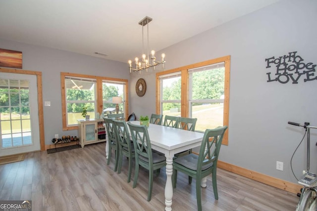 dining space with an inviting chandelier and light hardwood / wood-style flooring