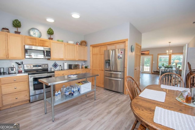 kitchen featuring pendant lighting, a notable chandelier, stainless steel appliances, and light hardwood / wood-style flooring