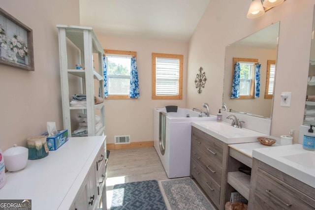 laundry area with light hardwood / wood-style floors, cabinets, independent washer and dryer, and sink