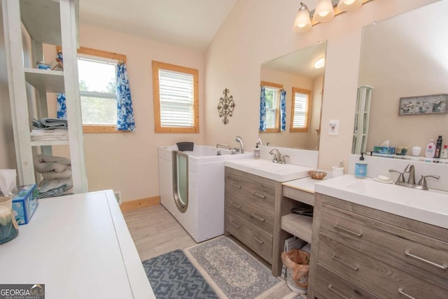 bathroom with hardwood / wood-style floors, vanity, separate washer and dryer, and lofted ceiling