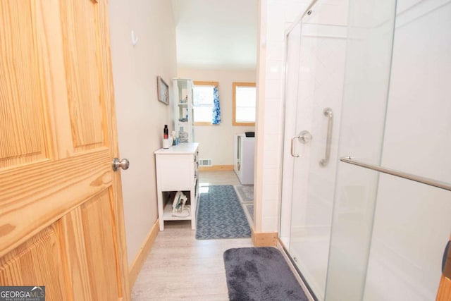 bathroom with wood-type flooring and a shower with door