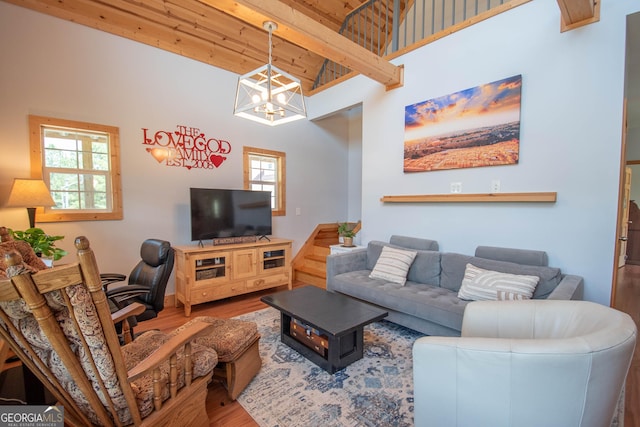 living room featuring beam ceiling, wood-type flooring, wooden ceiling, and a chandelier