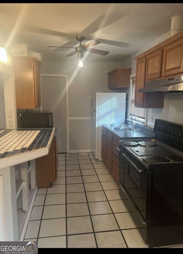 kitchen featuring tile counters, sink, white refrigerator, black / electric stove, and light tile patterned floors