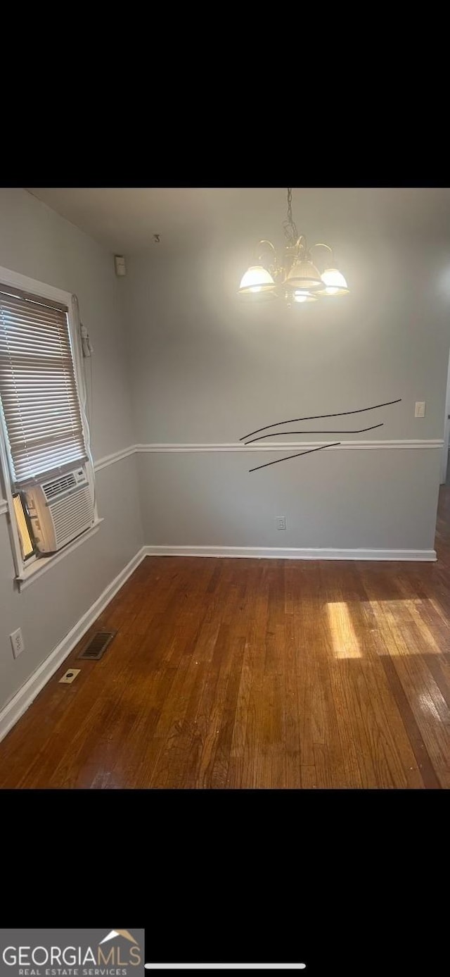 spare room featuring hardwood / wood-style flooring, cooling unit, and a chandelier